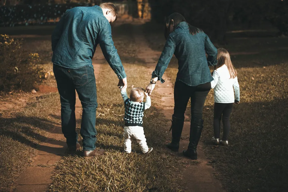 A family walking hand in hand along a sunny outdoor path