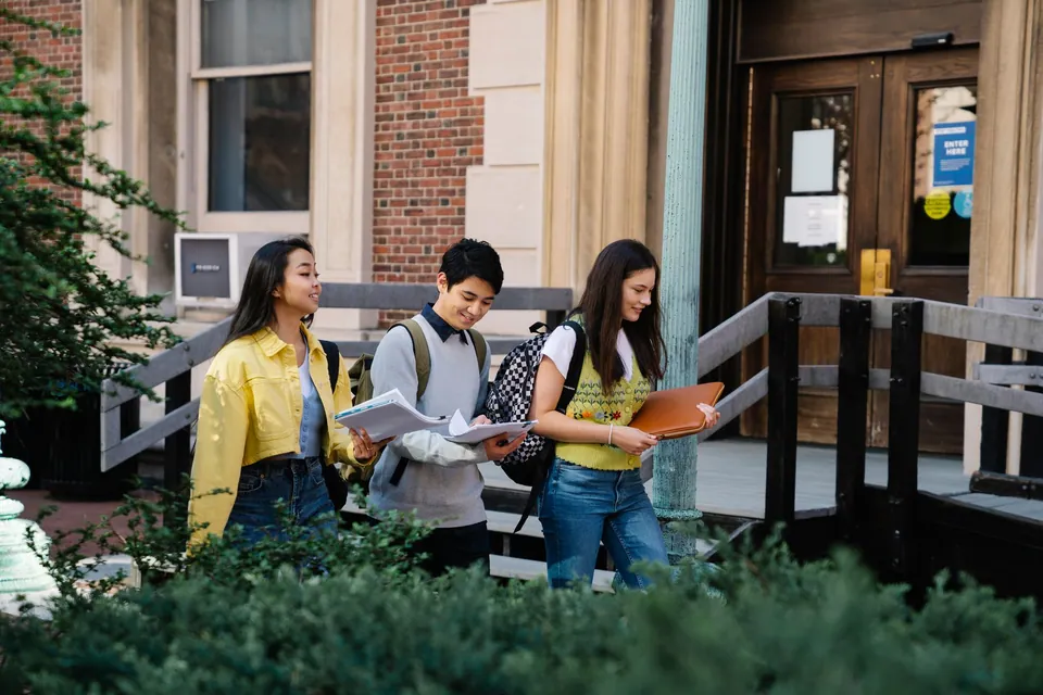 Three students walking outdoors on a university campus